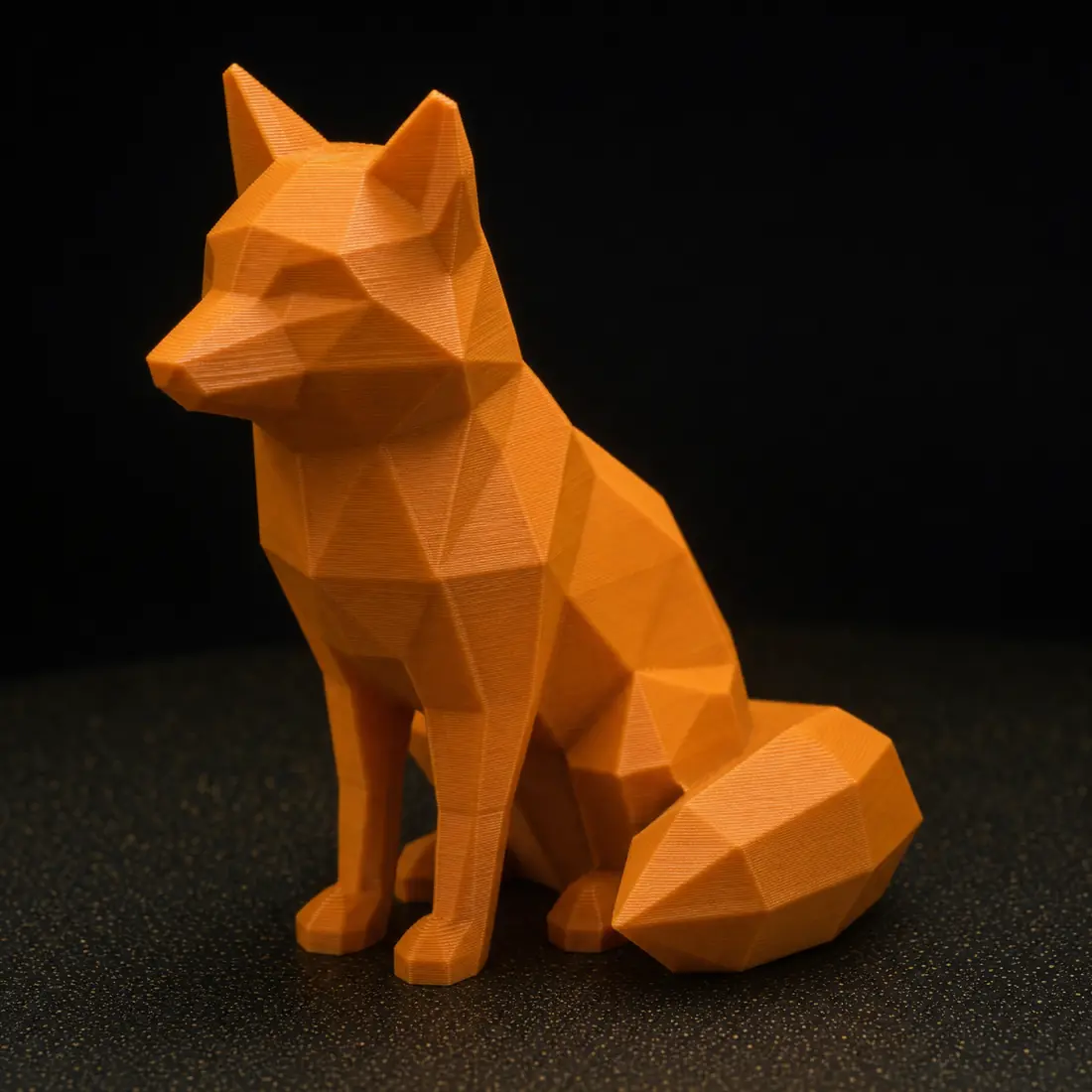 Un zorro low-poly impreso en PLA naranja sobre una cama PEI negra